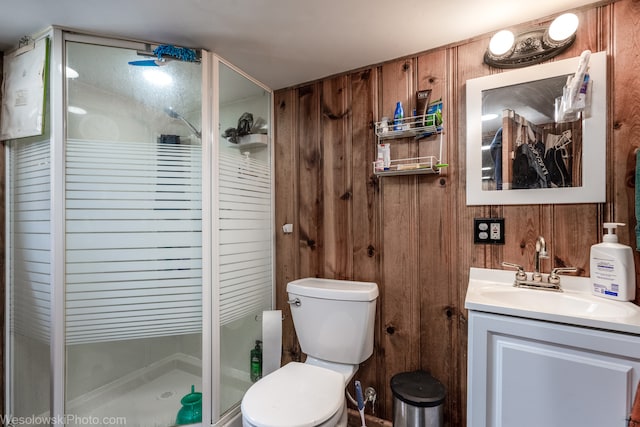 bathroom featuring vanity, wood walls, toilet, and a shower with door