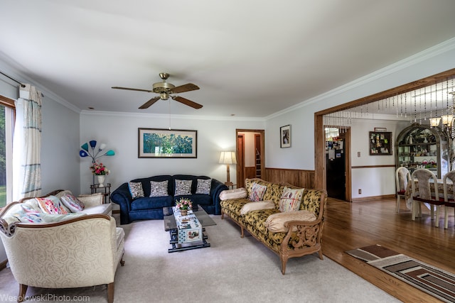 living room featuring wood-type flooring, wooden walls, ornamental molding, and ceiling fan