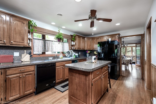 kitchen with a kitchen island, light wood-type flooring, a healthy amount of sunlight, and black appliances