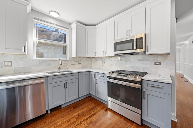 kitchen with gray cabinetry, stainless steel appliances, dark wood-type flooring, and sink