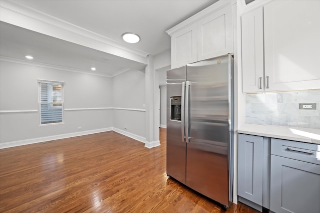 kitchen featuring white cabinets, stainless steel fridge with ice dispenser, crown molding, dark hardwood / wood-style flooring, and decorative backsplash