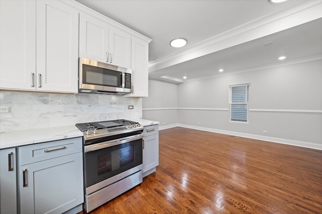 kitchen featuring dark wood-type flooring, tasteful backsplash, white cabinets, stainless steel appliances, and crown molding