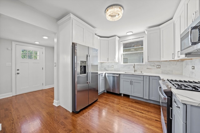 kitchen featuring decorative backsplash, gray cabinetry, stainless steel appliances, hardwood / wood-style flooring, and sink