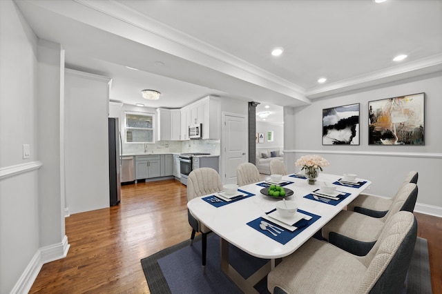 dining room featuring ornamental molding, dark wood-type flooring, and sink