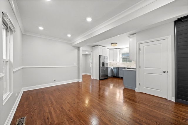 unfurnished living room featuring sink, crown molding, and dark wood-type flooring