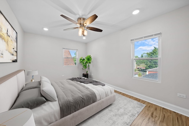 bedroom with multiple windows, ceiling fan, and hardwood / wood-style flooring