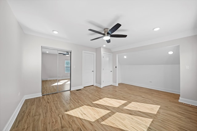 unfurnished bedroom with light hardwood / wood-style flooring, two closets, and ceiling fan