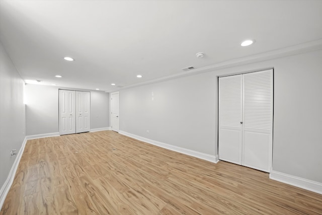 unfurnished bedroom with multiple closets and light hardwood / wood-style flooring