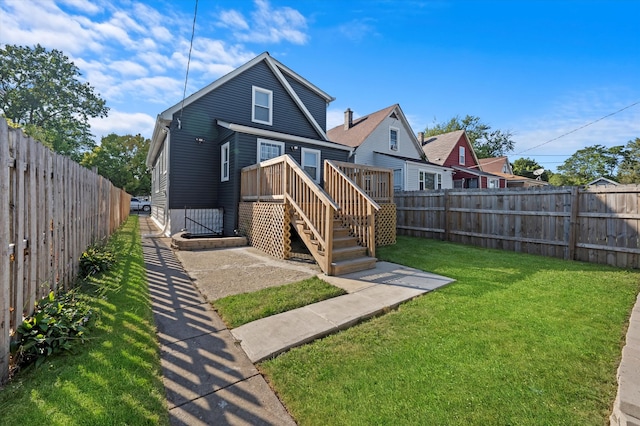 rear view of house featuring a wooden deck and a yard