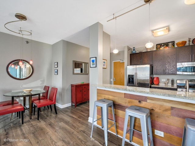 757 N Orleans St Unit 1612, Chicago, IL 60654 - kitchen with stainless steel appliances, dark wood-type flooring, a kitchen breakfast bar, dark brown cabinetry, and baseboards