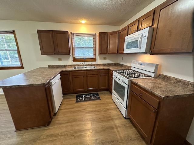 kitchen with kitchen peninsula, sink, plenty of natural light, and white appliances