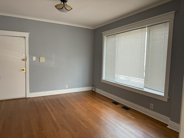 empty room featuring ornamental molding and hardwood / wood-style floors