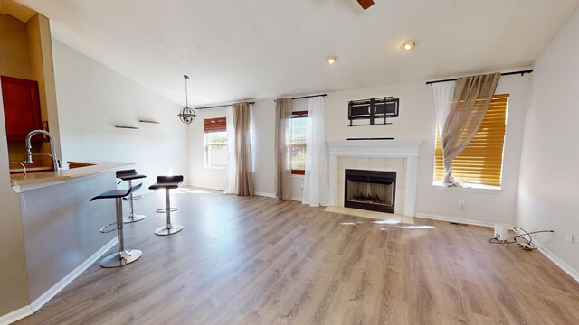 living room featuring light hardwood / wood-style flooring, lofted ceiling, a fireplace, and sink