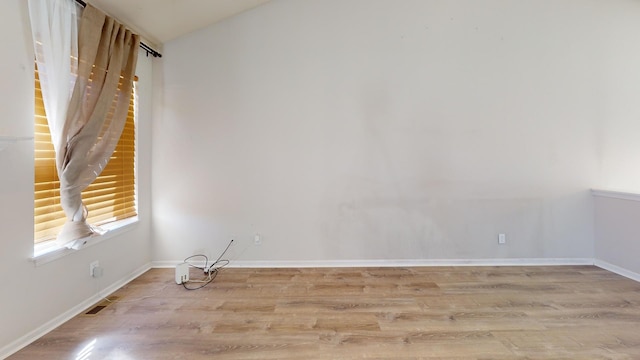 unfurnished room featuring light wood-type flooring and vaulted ceiling