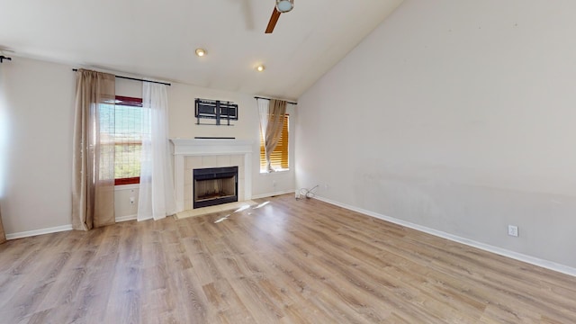 unfurnished living room featuring ceiling fan, light hardwood / wood-style flooring, vaulted ceiling, and a tile fireplace