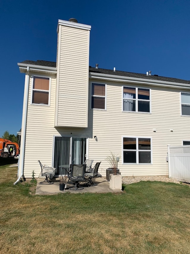 rear view of property with a lawn, central AC unit, and a patio area