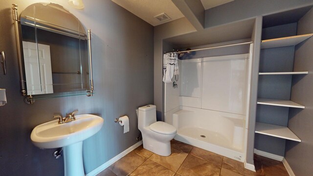 bathroom with walk in shower, toilet, and tile patterned floors