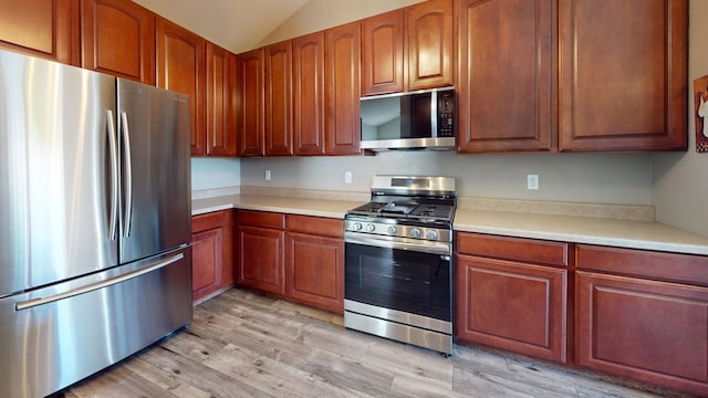 kitchen featuring lofted ceiling, light hardwood / wood-style flooring, and stainless steel appliances