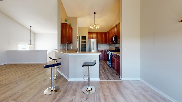 kitchen with hanging light fixtures, kitchen peninsula, light hardwood / wood-style flooring, appliances with stainless steel finishes, and a breakfast bar area