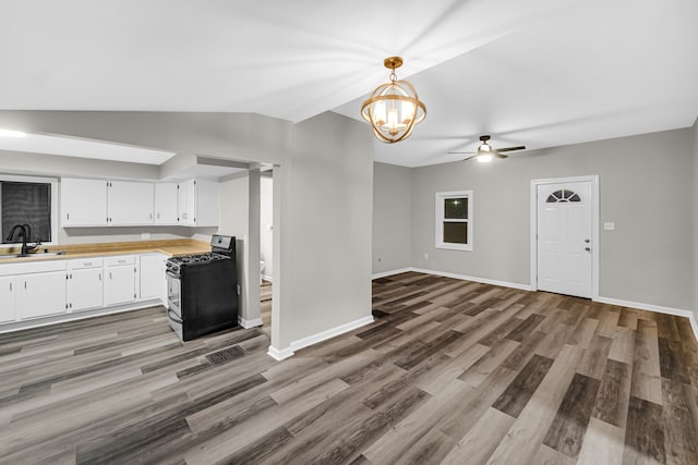 kitchen featuring white cabinets, ceiling fan with notable chandelier, pendant lighting, black range with gas cooktop, and sink