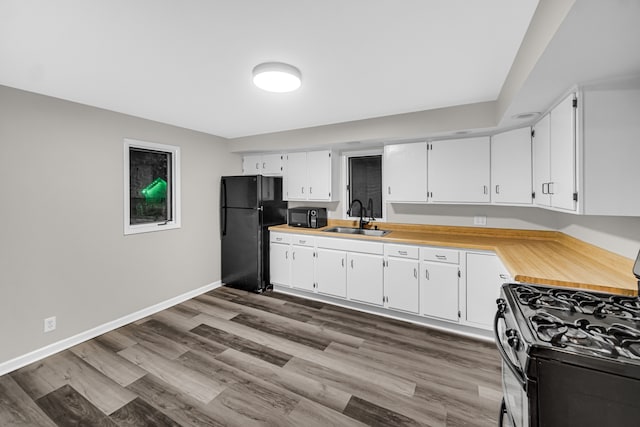 kitchen featuring white cabinets, black appliances, hardwood / wood-style floors, and sink