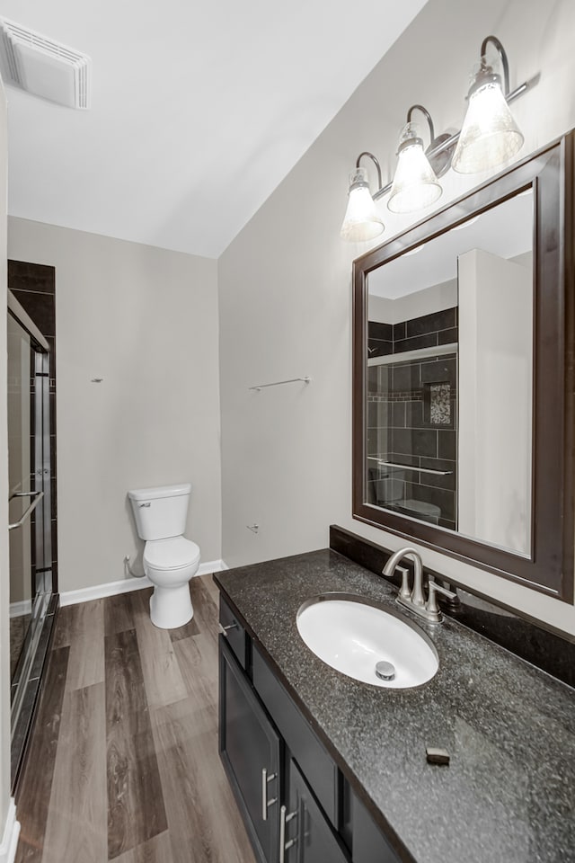 bathroom with wood-type flooring, vanity, toilet, and a shower with door