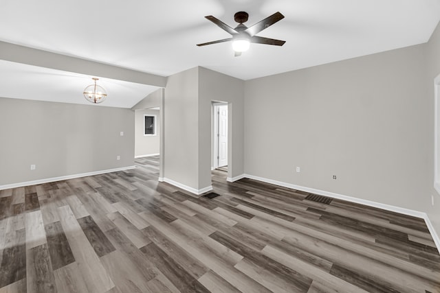 spare room with ceiling fan with notable chandelier, vaulted ceiling, and hardwood / wood-style floors