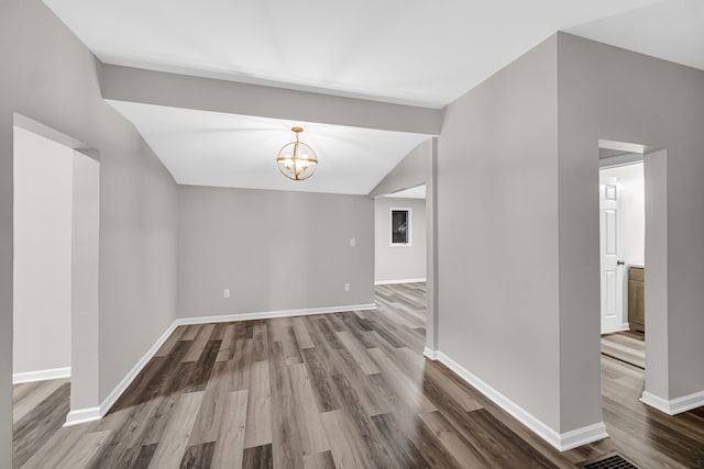 spare room with lofted ceiling, hardwood / wood-style floors, and a notable chandelier