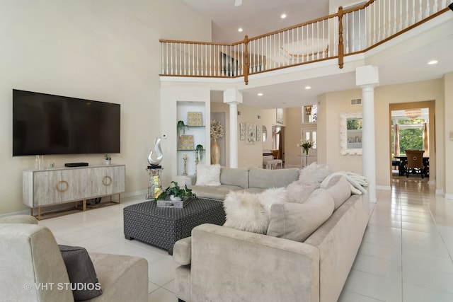 living room featuring light tile patterned flooring, decorative columns, and a high ceiling