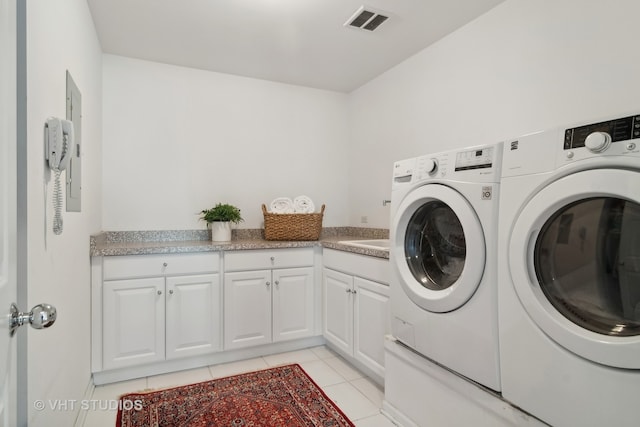 washroom with cabinets, light tile patterned floors, and washer and dryer