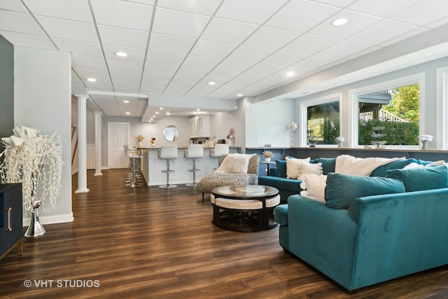 living room featuring a drop ceiling and dark hardwood / wood-style floors