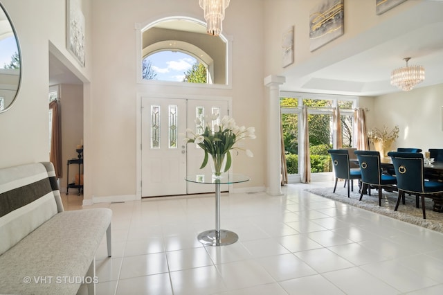 foyer entrance featuring decorative columns, light tile patterned flooring, a chandelier, and a wealth of natural light