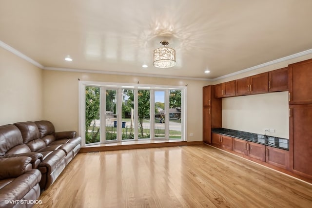 unfurnished living room with light wood-type flooring, crown molding, and an inviting chandelier