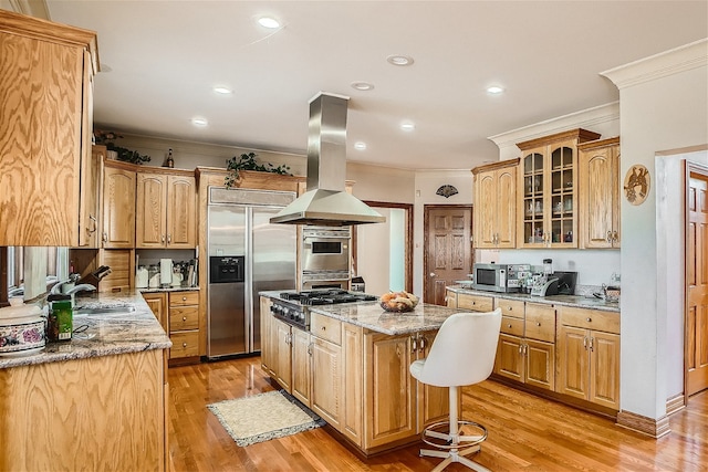 kitchen with light wood-type flooring, island exhaust hood, a kitchen island, stainless steel appliances, and light stone countertops