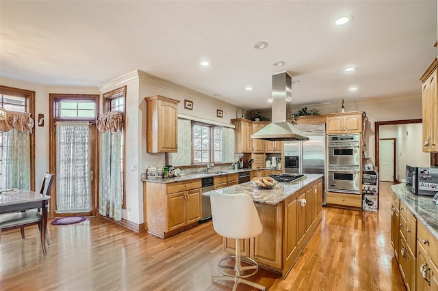 kitchen with light wood-type flooring, a center island, island range hood, stainless steel appliances, and light stone countertops