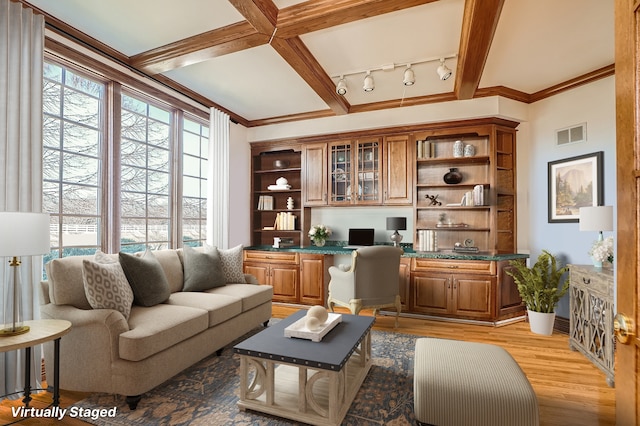 living room featuring built in desk, rail lighting, light wood-type flooring, beam ceiling, and ornamental molding