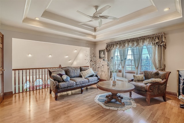 living room with ornamental molding, a tray ceiling, ceiling fan, and light hardwood / wood-style floors