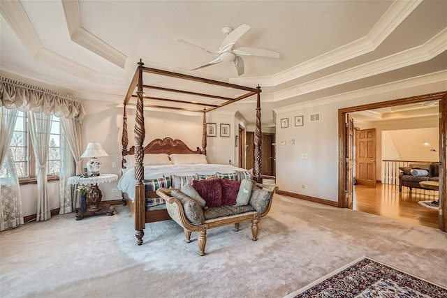 carpeted bedroom featuring a tray ceiling, ceiling fan, and crown molding