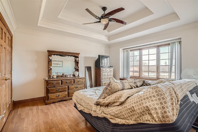 bedroom featuring light hardwood / wood-style flooring, a tray ceiling, ceiling fan, and ornamental molding