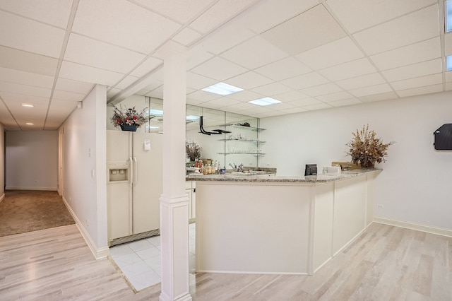 interior space with light hardwood / wood-style floors, white refrigerator with ice dispenser, white cabinets, light stone countertops, and a paneled ceiling