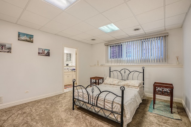 carpeted bedroom featuring a drop ceiling and connected bathroom