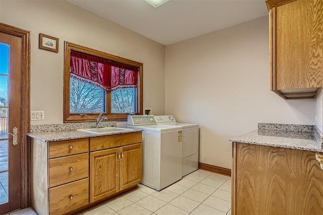 laundry area featuring washing machine and clothes dryer, light tile patterned flooring, a healthy amount of sunlight, and sink