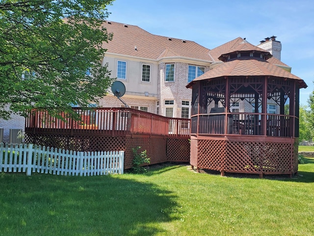 back of property featuring a deck, a gazebo, and a yard