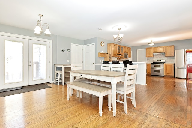 dining room with light wood-type flooring, a chandelier, and a wealth of natural light