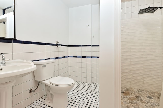 bathroom with toilet, tile walls, tile patterned flooring, and a tile shower