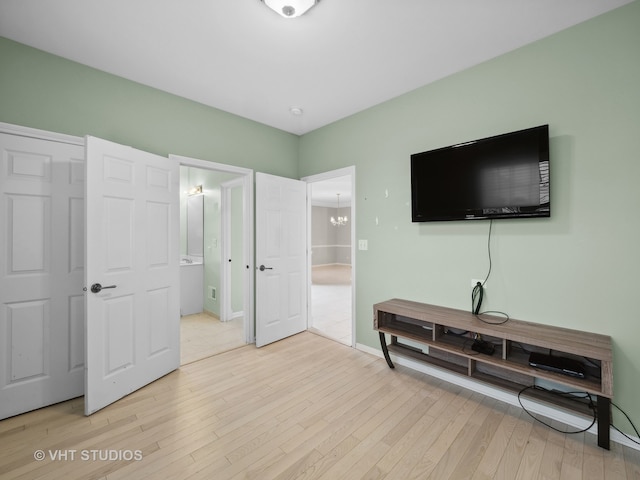 bedroom with ensuite bathroom, a chandelier, and light hardwood / wood-style flooring