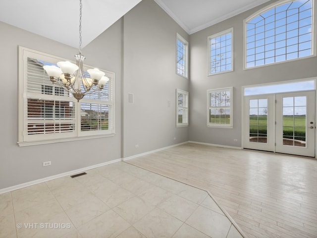 interior space featuring crown molding, light hardwood / wood-style flooring, a healthy amount of sunlight, and an inviting chandelier