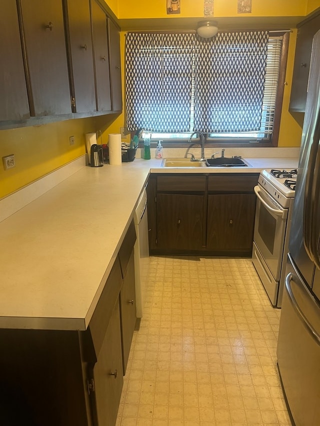 kitchen featuring appliances with stainless steel finishes, dark brown cabinetry, and sink