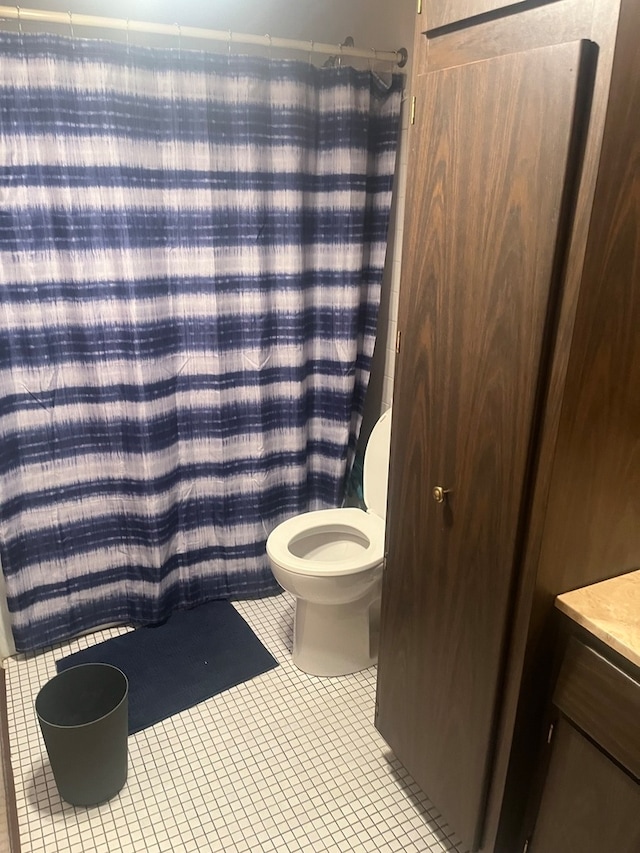 bathroom with tile patterned flooring, a shower with curtain, vanity, and toilet