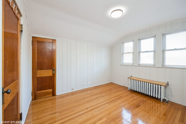 additional living space featuring hardwood / wood-style floors, radiator, and vaulted ceiling